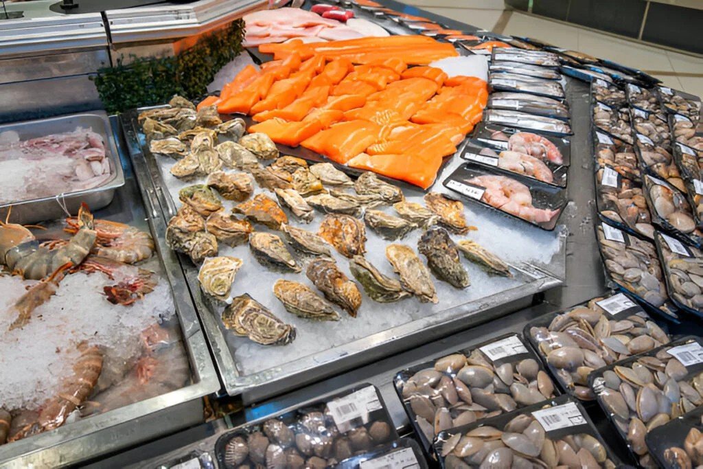 fresh seafood display with various shrimps salmon fillet oysters clams shellfish